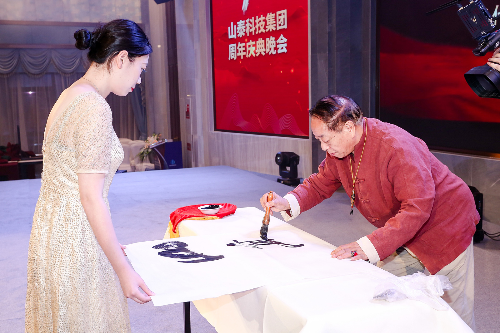 书画名家程俊良在山泰十周年庆典晚会现场书写“山高人为峰”